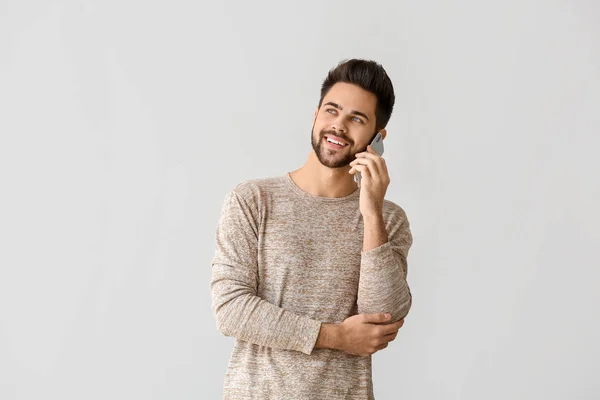 Feliz joven hablando por teléfono móvil sobre fondo gris — Foto de Stock