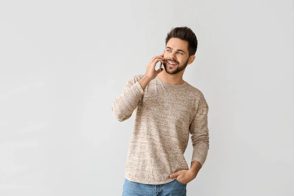 Feliz joven hablando por teléfono móvil sobre fondo gris — Foto de Stock