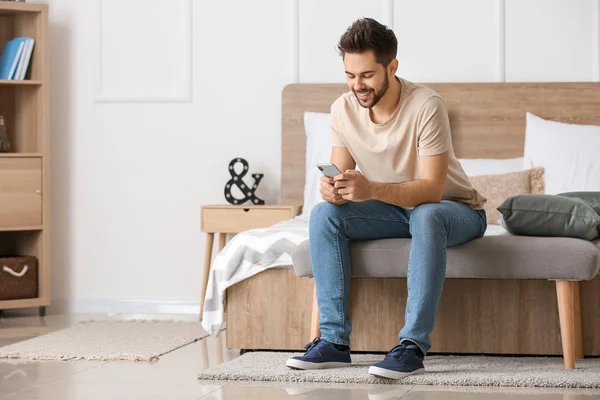 Happy young man with mobile phone at home — Stock Photo, Image