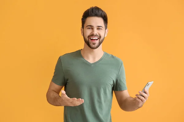 Счастливый молодой человек с мобильным телефоном на фоне цвета — стоковое фото