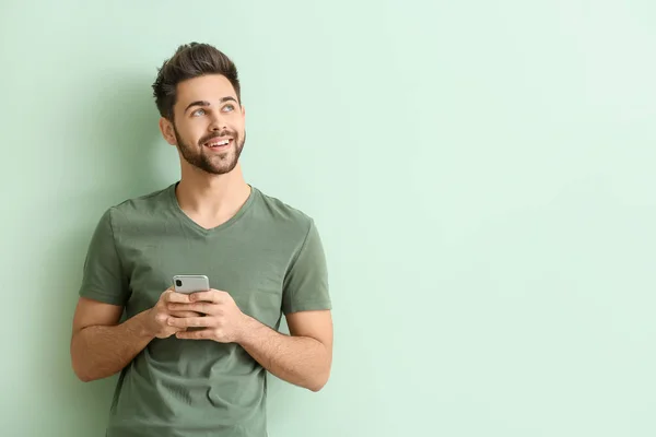 Boldog fiatal férfi mobiltelefon színes háttér — Stock Fotó