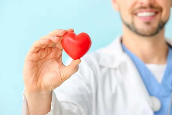 Männlicher Kardiologe mit rotem Herz auf farbigem Hintergrund, Nahaufnahme — Stockfoto