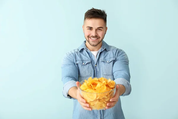 Jóképű fiatalember ízletes burgonya chips a színes háttér — Stock Fotó