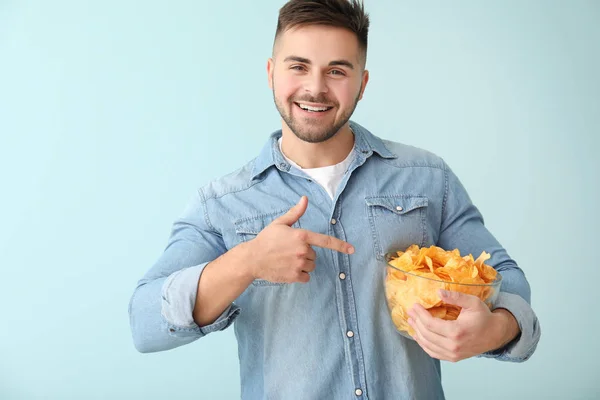 Joven guapo con sabrosas papas fritas sobre fondo de color —  Fotos de Stock