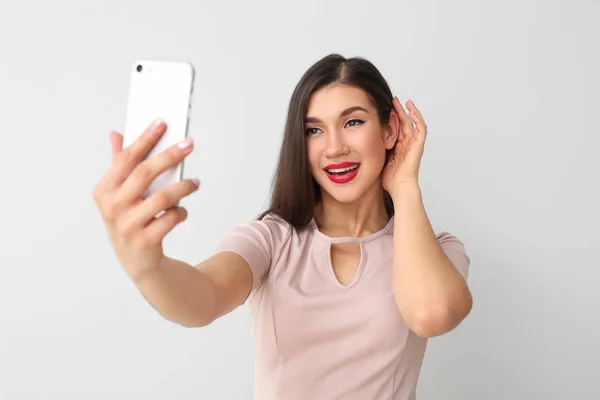 Krásná mladá žena přičemž selfie na světlém pozadí — Stock fotografie