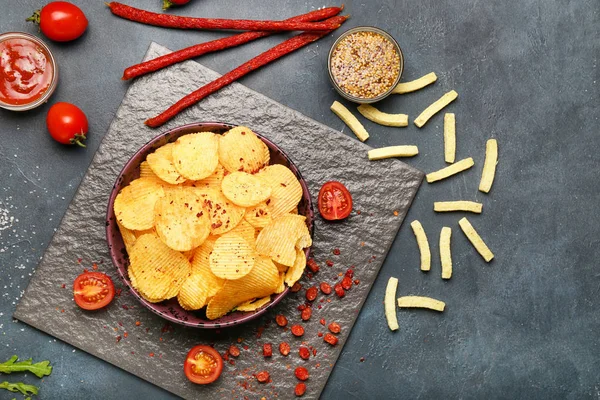Kompozice s chutnými bramborovými lupínky na tmavém pozadí — Stock fotografie