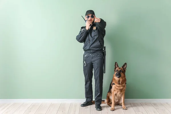 Policial masculino com cão perto de parede de cor — Fotografia de Stock