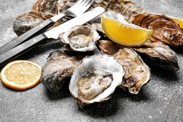 Tasty oysters with lemon on grey background — Stockfoto