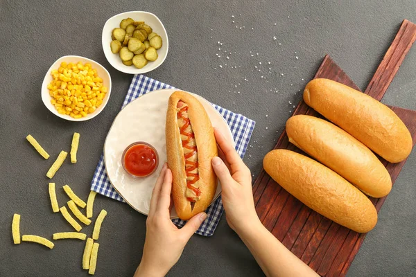 Woman eating tasty hot dog at table — Stock Photo, Image