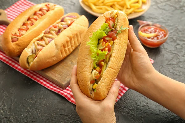 Žena s chutnými hot dogy u stolu — Stock fotografie
