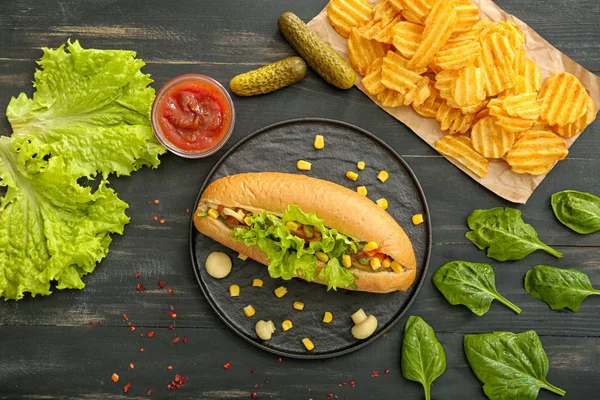 Tasty hot dog and potato chips on dark background — Stock Photo, Image