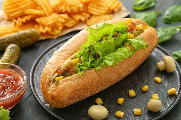 Talerz ze smacznym hot dogiem na stole — Zdjęcie stockowe