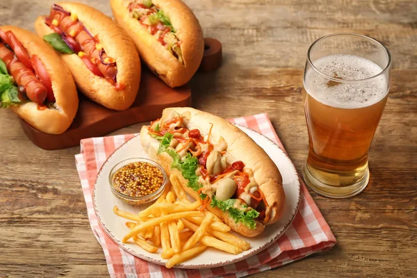 Tasty hot dogs with french fries and beer on wooden background — Stock Photo, Image