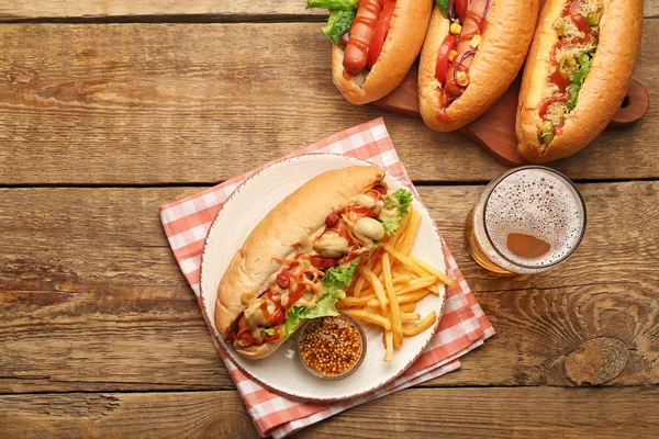 Tasty hot dogs with french fries and beer on wooden background — Stockfoto