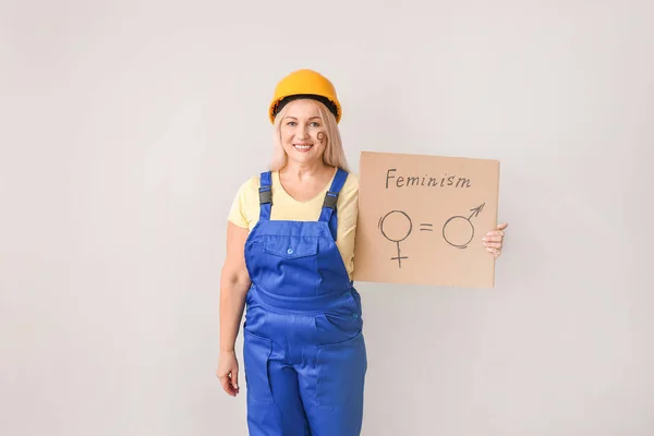 Worker holding cardboard with symbols of man and woman on light background. Concept of feminism — ストック写真