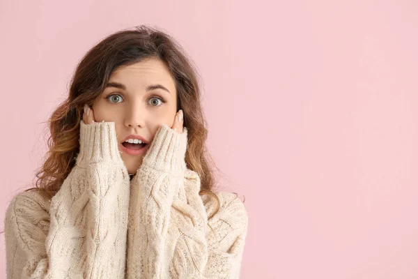 Vacker förvånad ung kvinna i varm tröja på färg bakgrund — Stockfoto