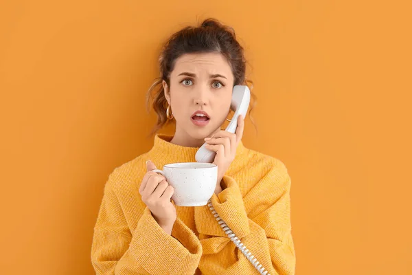 Bella giovane donna con una tazza di tè parlando per telefono contro lo sfondo di colore — Foto Stock