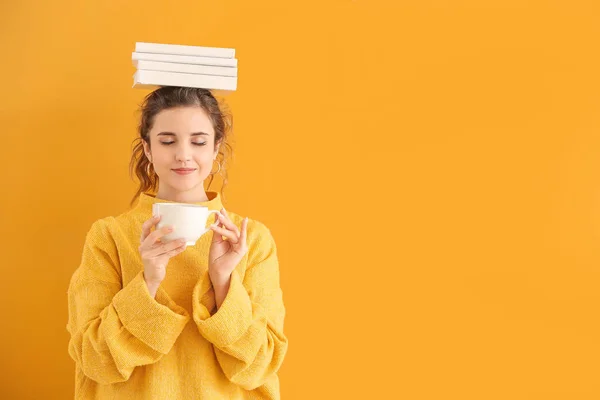 Bella giovane donna con libri e tè su sfondo a colori — Foto Stock