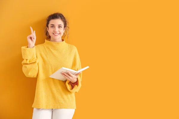 Mooie jonge vrouw in warme trui en met boek over kleur achtergrond — Stockfoto