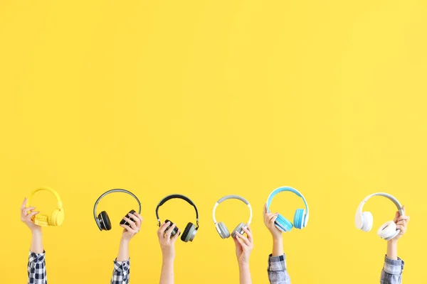 Manos con auriculares modernos sobre fondo de color — Foto de Stock
