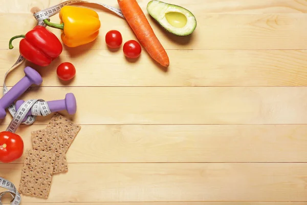 Different healthy food with measuring tape and dumbbells on wooden background. Diet concept — Stock Photo, Image