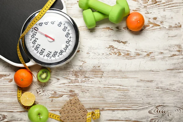 Different healthy food with measuring tape, scales and dumbbells on wooden background. Diet concept — Stok fotoğraf