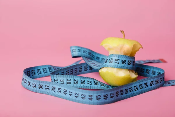 Apple core and measuring tape on color background. Diet concept — Stock Photo, Image