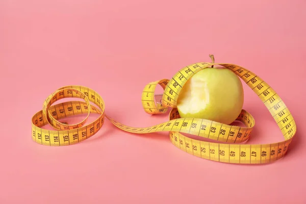 Bitten apple and measuring tape on color background. Diet concept — Stock Photo, Image