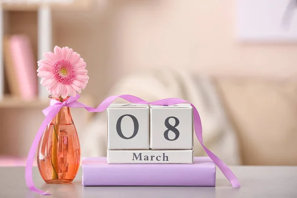 Kalender med datum för internationella kvinnodagen, blomma och bok på bordet i rummet — Stockfoto