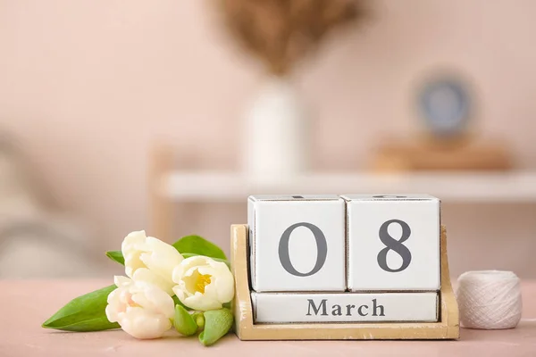 Calendar with date of International Women's Day and flowers on table in room — Stock Photo, Image
