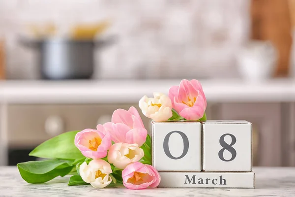Календарь с датой Международного женского дня и цветами на столе на кухне — стоковое фото