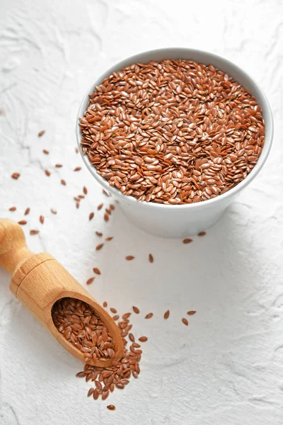 Tigela e colher com sementes de linho no fundo branco — Fotografia de Stock