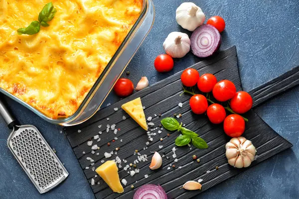 Tasty lasagna with vegetables, cheese and spices on dark background — Stock Photo, Image