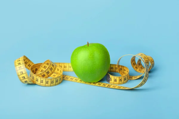 Apple and measuring tape on color background. Diet concept — Stock Image Apple and measuring tape on color background. Diet concept Stock Image