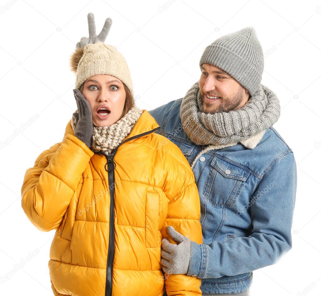 Portrait of emotional couple in winter clothes on white background