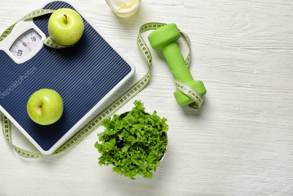 Different healthy food with measuring tape, scales and dumbbells on white wooden background. Diet concept