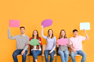 Renk arkaplanı üzerinde boş konuşma baloncukları olan bir grup genç