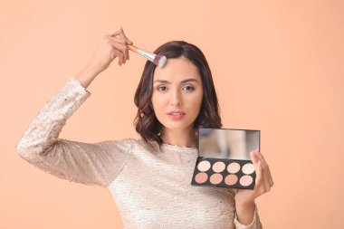 Renkli arka plana makyaj yapan güzel genç bir kadın.