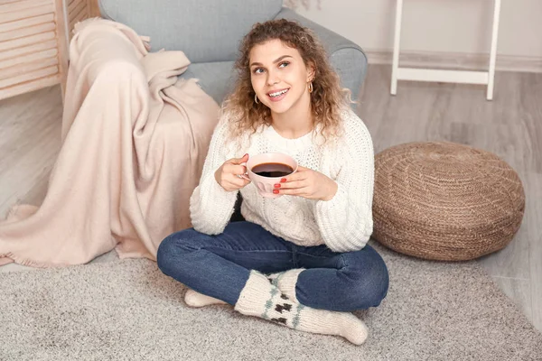 Beautiful young woman in warm sweater drinking tea at home — Stock Photo, Image