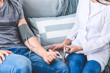Doktor evdeki genç adamın kan basıncını ölçüyor.