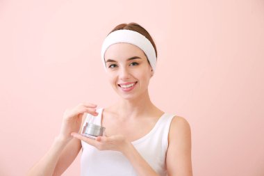 Renkli arka planda krema kavanozu olan güzel genç bir kadın.