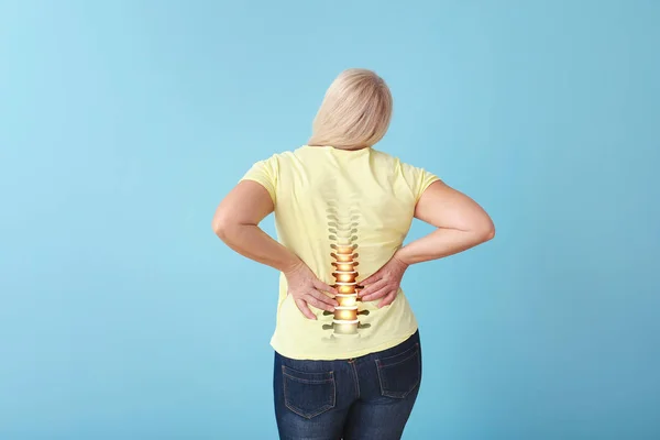Mujer madura que sufre de dolor de espalda en el fondo de color — Foto de Stock