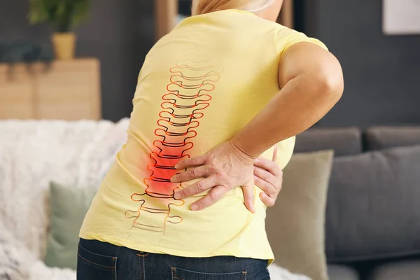 Mulher madura que sofre de dor nas costas em casa — Fotografia de Stock