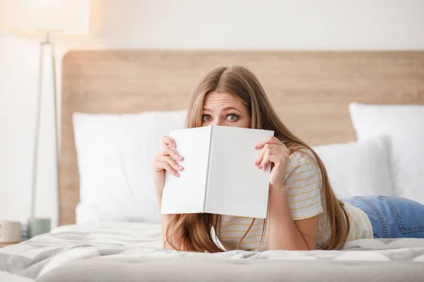 Beautiful young woman reading book at home — Stock Photo, Image