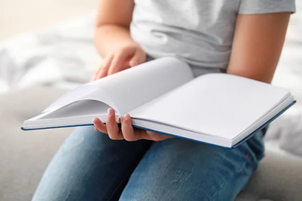Симпатична дівчинка читає книгу вдома, крупним планом — стокове фото