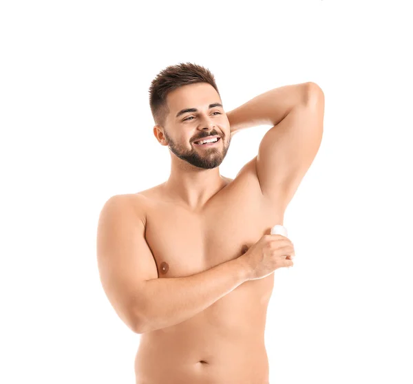 Bello giovane uomo utilizzando deodorante su sfondo bianco — Foto Stock