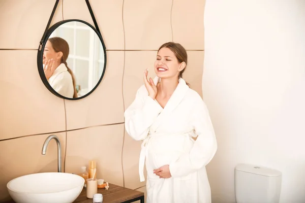 Hermosa mujer embarazada aplicando crema en el baño — Foto de Stock