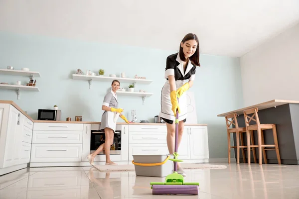 Beautiful young chambermaids cleaning kitchen — 스톡 사진