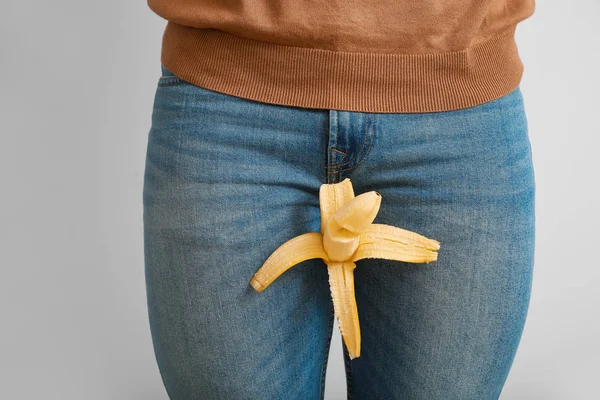 Young man with banana on grey background. Urology concept — Stock Photo, Image