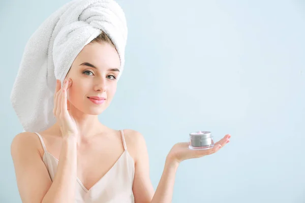 Hermosa mujer joven con tarro de crema sobre fondo de color — Foto de Stock